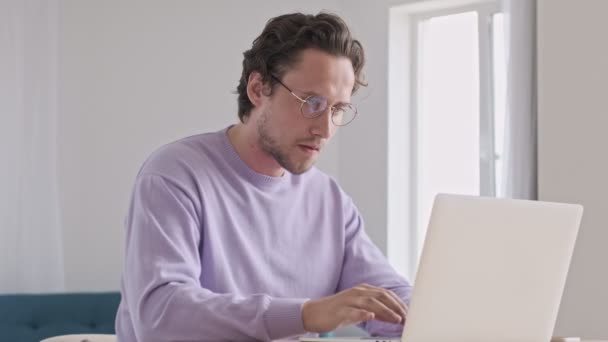 Homem Bonito Concentrado Óculos Usando Computador Portátil Mesa Casa — Vídeo de Stock