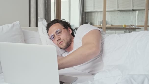 Tranquilo Hombre Guapo Gafas Usando Computadora Portátil Mientras Está Acostado — Vídeo de stock