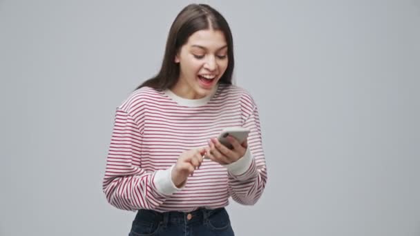 Glimlachen Aantrekkelijke Brunette Vrouw Spelen Smartphone Verheugen Dat Grijze Achtergrond — Stockvideo