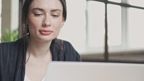 一位面带微笑的年轻女商人坐在办公室里用手提电脑工作 这是她的近照 — 图库视频影像