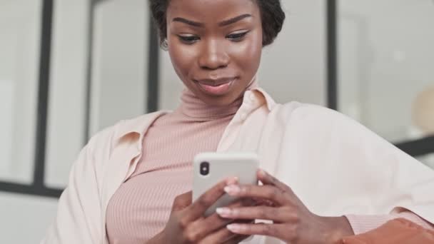 Una Joven Africana Feliz Complacida Está Usando Teléfono Móvil Mientras — Vídeos de Stock