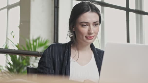 一位快乐 友善的年轻女商人在办公室工作时 正在用手提电脑与视频连接通话 — 图库视频影像