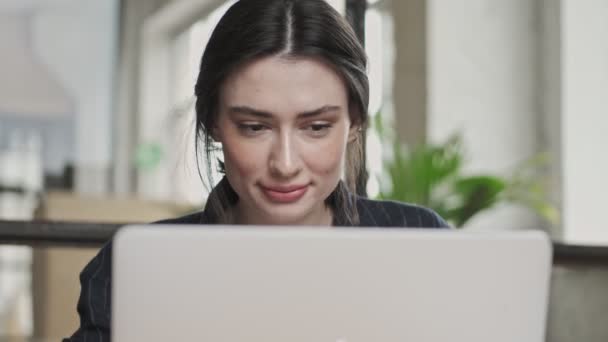 一位面带微笑的年轻女商人在办公室工作时 正在使用她的银色笔记本电脑 这是她的近照 — 图库视频影像