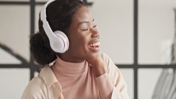 Смеющаяся Эмоциональная Молодая Африканка Наушниках Слушает Музыку Танцует Дома — стоковое видео