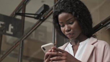 Afro-amerikan bir iş kadınının ofisteki akıllı telefonunu kullanmasının alttaki görüntüsü...