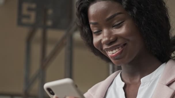 一位年轻貌美的非洲裔美国女商人正在用她的智能手机在办公室里工作 — 图库视频影像
