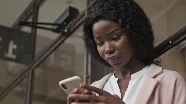 一位专注于此的年轻非洲裔美国女商人正在办公室里使用智能手机 — 图库视频影像