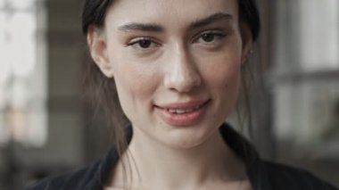 Genç ve başarılı bir iş kadınının yakın çekim görüntüsü ofiste duran kameraya bakıyor.