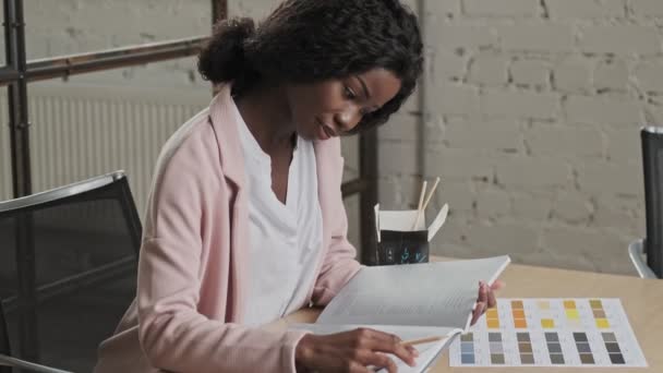 Μια Ελκυστική Νεαρή Αφροαμερικανίδα Επιχειρηματίας Σχεδιαστής Εργάζεται Έντυπα Έγγραφα Ενώ — Αρχείο Βίντεο