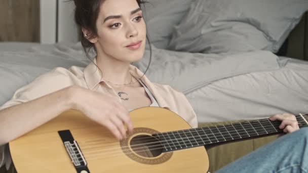 Evde Konsantre Olmuş Bir Kadın Gitar Çalarken Yatağın Yanında Oturuyor — Stok video