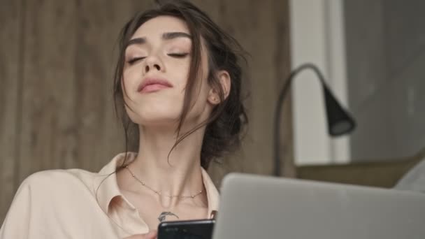 아름다운 여자가 노트북 컴퓨터와 전화를 사용하면서 집안에 — 비디오