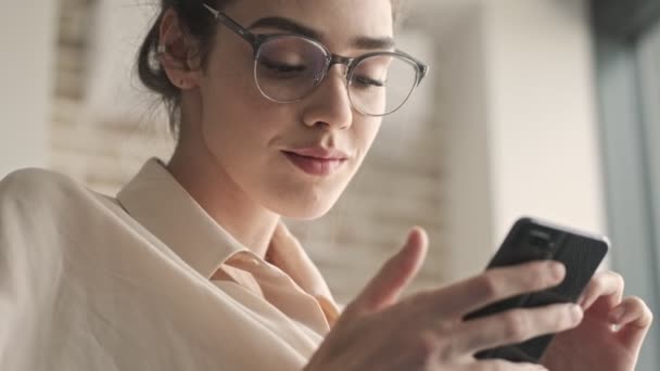 Joven Mujer Bonita Optimista Sentada Casa Usando Teléfono Móvil — Vídeo de stock