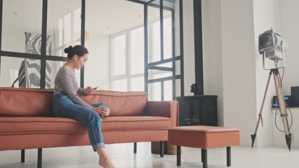 Sorrindo Mulher Asiática Bonita Usando Smartphone Enquanto Sentado Sofá Casa — Vídeo de Stock