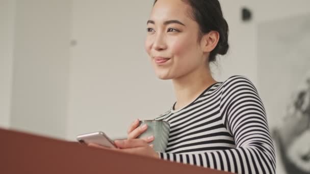 Usmívající Hezká Asijská Žena Pomocí Smartphone Dívá Pryč Zatímco Sedí — Stock video