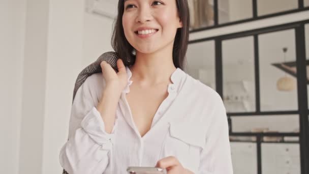 Alegre Mulher Asiática Bonita Usando Smartphone Olhando Para Longe Enquanto — Vídeo de Stock