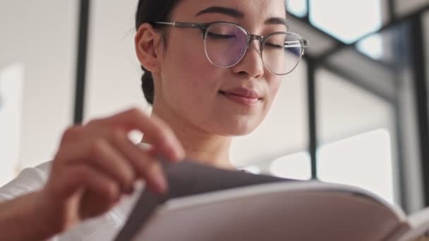 Agradado Elegante Bonita Asiática Mulher Óculos Leitura Revista Enquanto Sentado — Vídeo de Stock