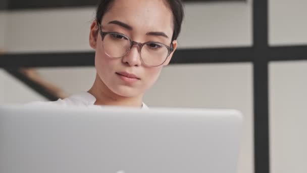 Gözlüklü Zarif Asyalı Kadın Evdeki Koltukta Otururken Dizüstü Bilgisayar Kullanıyor — Stok video