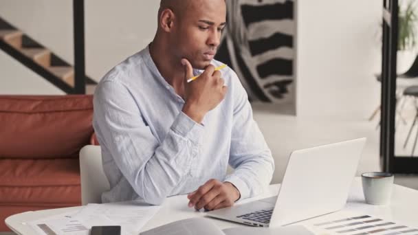 一位注意力集中的非洲裔美国人在家里工作时 坐在客厅的桌子旁 一边用笔记本电脑 — 图库视频影像
