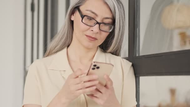 Een Gefocuste Volwassen Vrouw Met Een Bril Gebruikt Haar Smartphone — Stockvideo