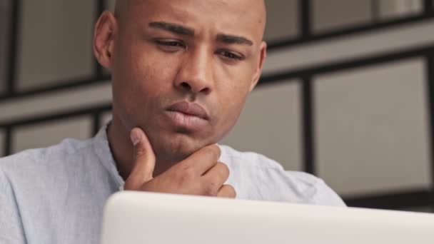 一位注意力集中的非洲裔美国人的近照是他坐在家中客厅里的银色笔记本电脑 — 图库视频影像