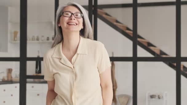 Śmiejąca Się Szczęśliwa Dojrzała Kobieta Okularach Pozuje Spogląda Kamerę Salonie — Wideo stockowe
