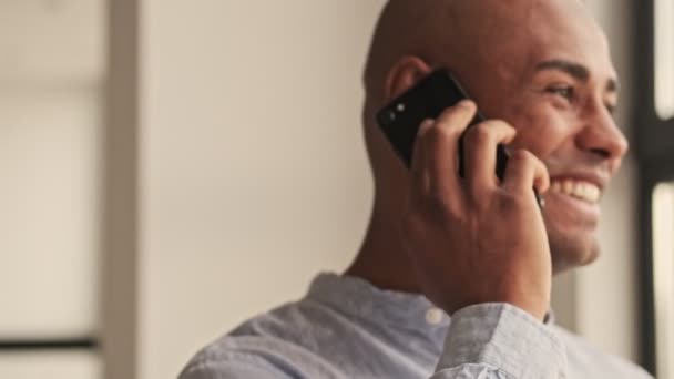 Homme Afro Américain Souriant Parle Sur Son Téléphone Dans Salon — Video