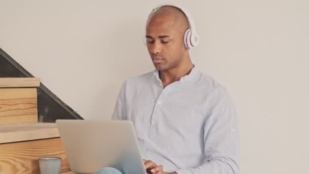 Mutlu Rahat Kablosuz Kulaklıklı Bir Afrikalı Amerikalı Evdeki Merdivenlerde Laptopunu — Stok video