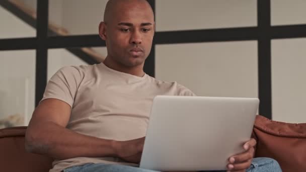 Hombre Afroamericano Concentrado Concentrado Está Usando Portátil Sentado Sofá Sala — Vídeos de Stock