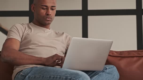 Hombre Afroamericano Guapo Está Mirando Portátil Sentado Sofá Sala Estar — Vídeos de Stock