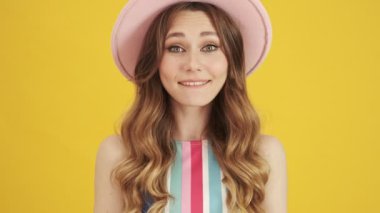 Pembe şapkalı güzel bir genç bayanın yakından görüntüsü sarı bir arka planda izole edilmiş sevinç dolu.