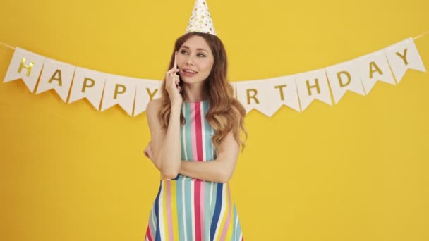 Emocjonalnie Podekscytowana Urodzinowa Kobieta Rozmawia Swoim Smartfonie Stojąc Żółtym Tle — Wideo stockowe