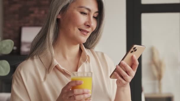 Uma Mulher Madura Satisfeita Feliz Está Bebendo Suco Laranja Enquanto — Vídeo de Stock