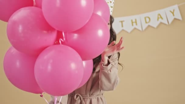 Eine Fröhliche Frau Einem Partykegel Lugt Aus Vielen Rosafarbenen Luftballons — Stockvideo