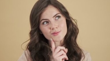 Güzel bir kadının yakın plan görüntüsü, bej bir arka plan üzerinde izole edilmiş bir şeyi düşünmektir.