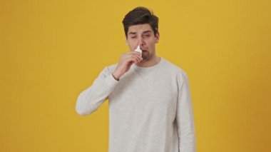 Sprey kullanan ve sarı arka planda daha iyi hisseden hasta bir adamın burnu akmış.