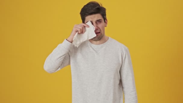 Nieszczęśliwy Chory Człowiek Alergią Wycierający Oczy Papierową Chusteczką Żółtym Tle — Wideo stockowe