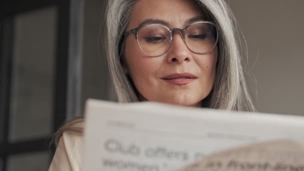 Närbild Vacker Mogen Kvinna Med Glasögon Läser Tidning Som Sitter — Stockvideo