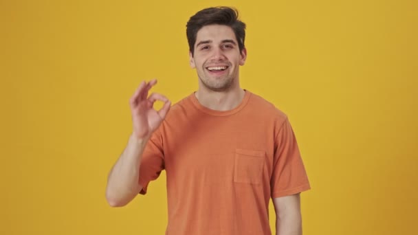Glimlachende Knappe Man Shirt Met Teken Gebaar Camera Gele Achtergrond — Stockvideo