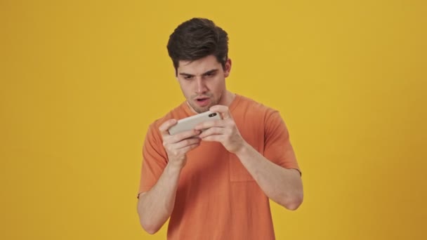 Sério Bonito Homem Vestindo Shirt Jogando Smartphone Sobre Fundo Amarelo — Vídeo de Stock