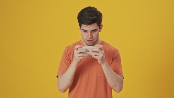 Ernstige Ontevreden Knappe Man Shirt Spelen Smartphone Gele Achtergrond — Stockvideo
