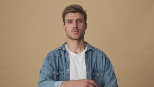Leende Ung Man Står Med Armarna Över Den Beige Väggen — Stockvideo