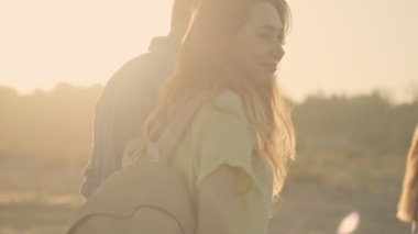 Güzel bir çiftin yakın çekimi. Erkek ve kadın arkadaşlarıyla sahilde yürüyorlar.