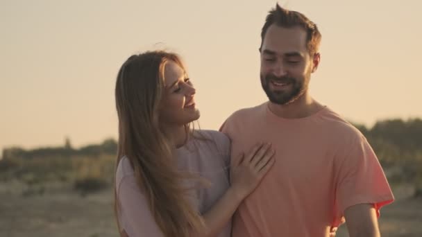 美しいカップルの男と女が一緒にビーチを歩いていて抱き合っている — ストック動画