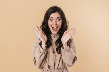 Sevinçli çekici bir kadının bej arka planda izole edilmiş bir şekilde kamerada şaşkınlığını ifade etmesi.