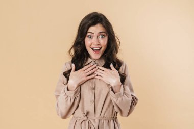 Heyecanlı güzel bir kadının bej arka planda izole edilmiş bir şekilde kamerada şaşkınlığını ifade etmesi.