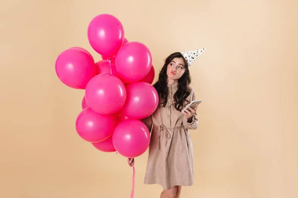 Imagem Mulher Confusa Usando Celular Enquanto Posando Com Balões Rosa — Fotografia de Stock