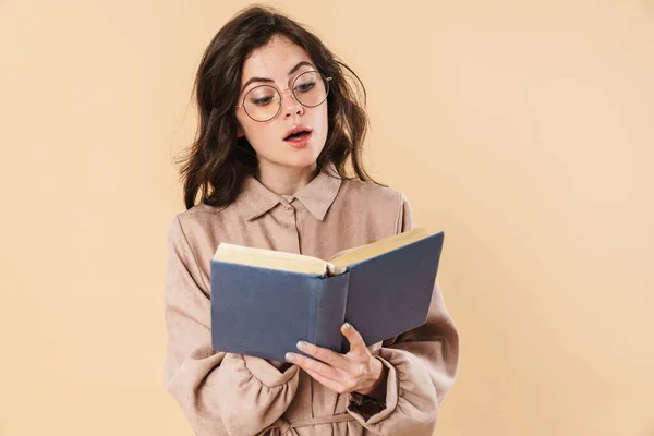 眼镜中惊讶的高加索女人的形象 在米色背景下孤立地阅读书籍 — 图库照片
