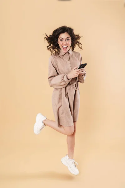 Imagen Mujer Agradable Emocionada Saltando Mientras Utiliza Teléfono Celular Aislado —  Fotos de Stock