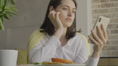 Evde kahvaltı yaparken cep telefonu kullanan inanılmaz konsantre bir kadın.