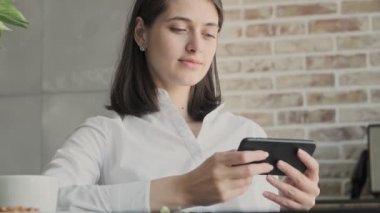 Evde cep telefonu kullanan genç konsantre iş kadını.